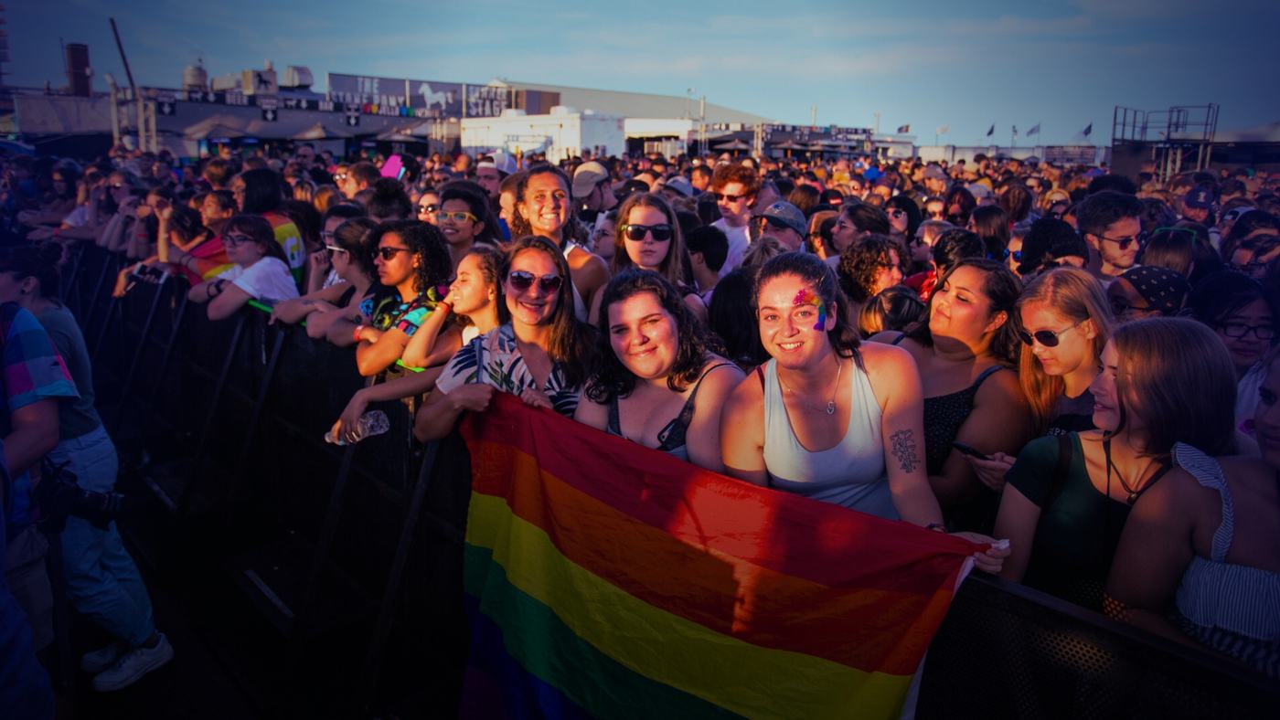 A crowd at a show holding a rainbow flag